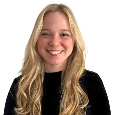 Smiling woman with long wavy blonde hair wearing a black top against a white background (head-and-shoulders portrait).]